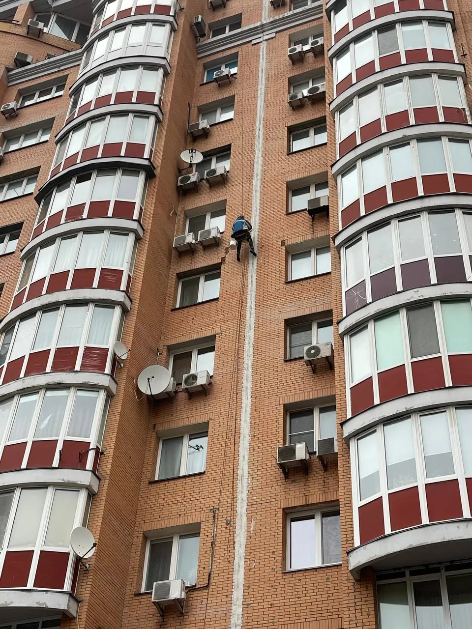 Альпініст герметизує міжпанельні шви на фасаді багатоповерхівки